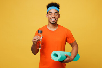 Young fitness trainer instructor sporty man sportsman wear orange t-shirt hold caremat drink water...