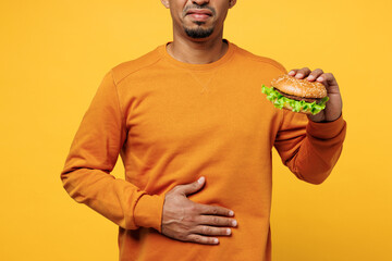 Close up cropped sick sad young man he wear orange sweatshirt casual clothes eat fast food burger...