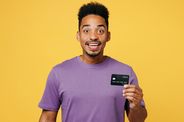 Young surprised man of African American ethnicity he wears purple t-shirt casual clothes hold in...