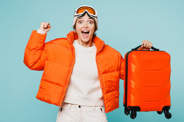 Traveler happy skier woman wear padded windbreaker jacket ski goggles mask hold suitcase bag...