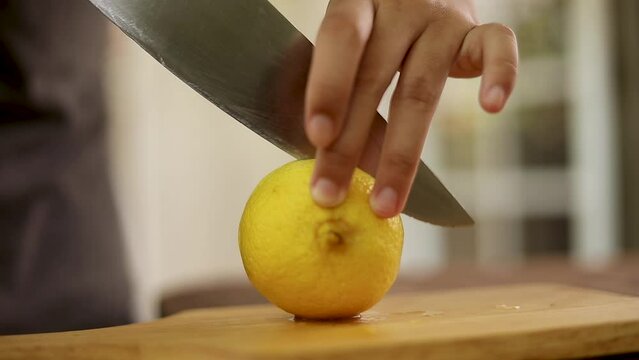 Woman's hand cutting a lemon in half on a cutting board Healthy foods that contain vitamin C

