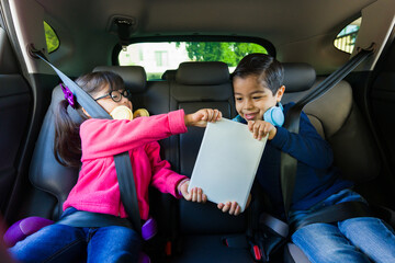 Cheerful kids on a road trip playing with the tablet