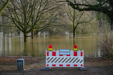 German warning sign in front of a path that ends in the flood waters of the river Leine. Hochwasser...
