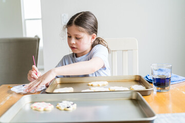 Obraz na płótnie Canvas Little Girl Spells 'Sorry' on Iced Sugar Cookies