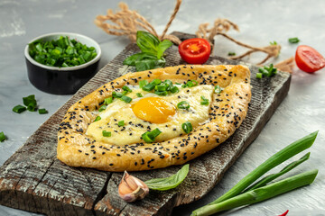 Khachapuri cheese and egg filled bread on a wooden board, top view. copy space