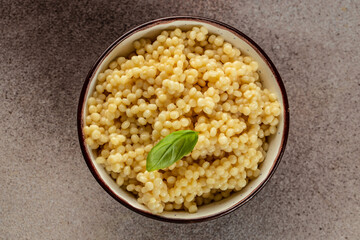 Boiled Ptitim Israeli pasta on a light background top view. copy space