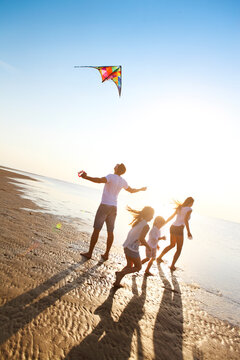 Happy young family with flying a kite on the beach