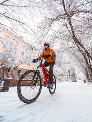 A man rides a bicycle in a snowy winter city. Active lifestyle in winter