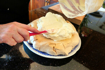 Cream being spread onto the meringue base made from whipped up egg white and caster sugar
