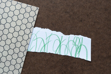 mixed media background (scrapbooking paper with hexagonal pattern, torn strip with green cursive lines, and dark brown board