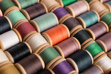 Sewing background from above. Background from colored cotton threads on spools. Materials for needlework. Shelf with multi-colored threads for sewing	 - Powered by Adobe