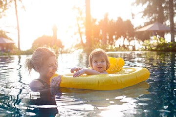 Cute little girl learning to swim with mother in pool