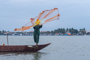 A man throws a fishing net to introduce local activities to tourists in Cam Thanh, Hoi An, Vietnam