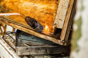 Processing of bee frames and hives for the honey harvest season. Firing the wooden parts of the hive with a blowtorch. Beekeeping work in the spring and after winter. - obrazy, fototapety, plakaty
