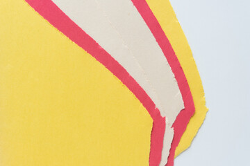 torn yellow, red, and antique white construction paper sheets arranged in staggered form on blank...