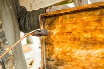 Processing of bee frames and hives for the honey harvest season. Firing the wooden parts of the...