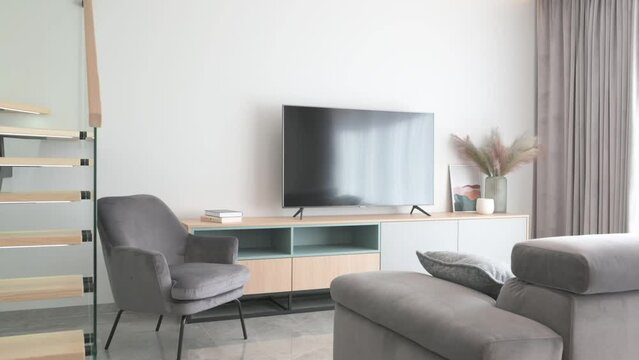 Smooth horizontal span of living room in bright modern house with large TV and grey furniture
