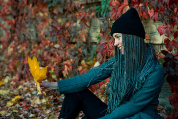 Portrait of a young beautiful girl with a smile on her face in an autumn park against a background...