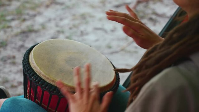 person with dreadlocks play tribal reggae at small African hand drum djembe