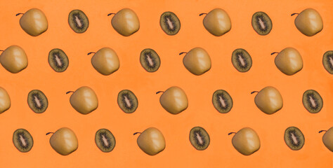 Green apple and kiwi on the orange background. Pattern. Flat lay.