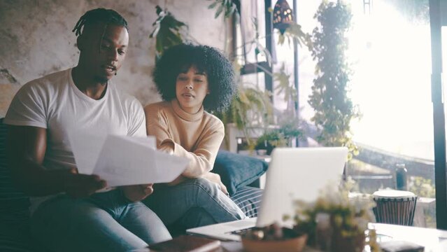 Black couple, laptop and documents in finance, budget planning or expenses on sofa at home. African man and woman with paperwork on computer for financial discussion or bills together at house