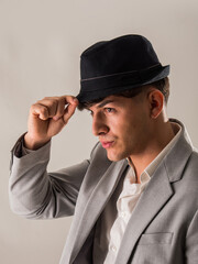 Attractive elegant young man with business suit and fedora hat, on white, looking away, seen sideways