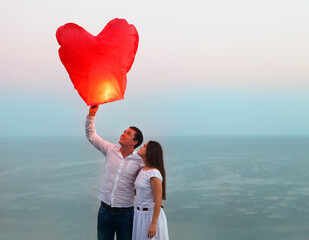 Young couple start a red Chinese sky lantern in the dusk © Dasha Petrenko
