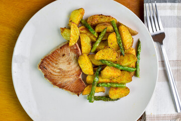 tuna steak  served with  potato wedges and asparagus