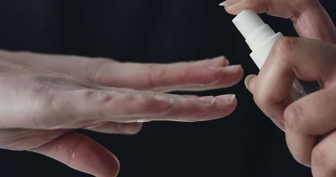 People, hands and spraying bottle on mockup space for disinfection, hygiene or cleaning on a dark studio background. Closeup of person and sanitizer or detergent on palms for bacteria or germ removal