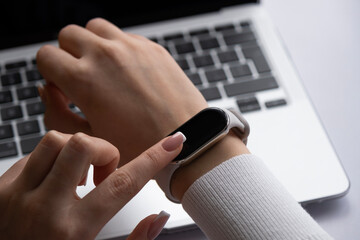 Woman using smart watches at the office with laptop backgrounds