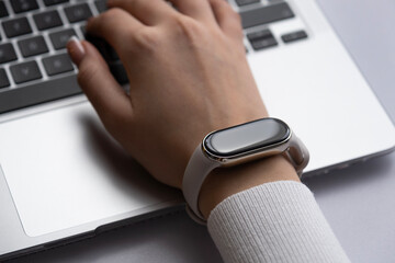 Woman working on a laptop with a smart watch on a wrist