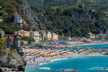 Monterosso, Italy, July 27, 2023. Beach and parasols in front of the giant, statue of the giant god...