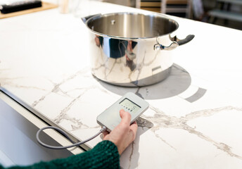 Invisible induction hob. An unrecognizable woman controls a remote control to heat a pot inside a...