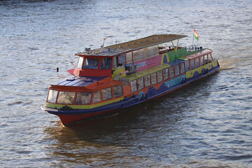 Budapest, a colorful boat is floating on the water near a dock and a flag pole in the background of the photo