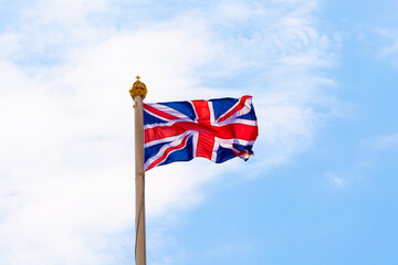 Waving United Kingdom flag on blue sky.