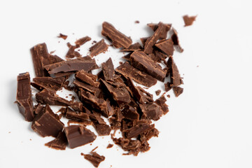 Chunks of dark chocolate separated on a white background.Small chunks of chocolate are sliced.