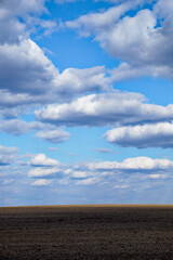 Fototapeta premium An expanse of tilled earth reaching to the horizon under a partly cloudy sky.
