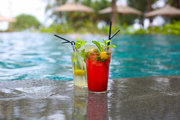 Classical and Strawberry Mojito cocktail at the edge of a resort pool