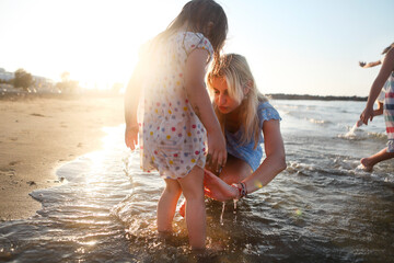 Little girl with mother on sea beach - obrazy, fototapety, plakaty