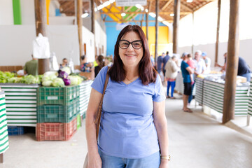 Brazilian mature woman at a vegetable market, smiling for the camera. Radiates warmth and...