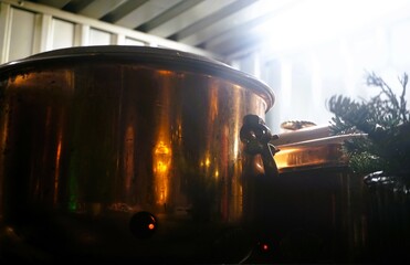 Brauer Glühweintopf aus Messing mit goldener Lichtspiegelung auf Herd am überdachten...