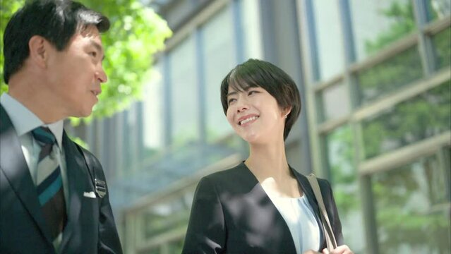 ビジネス街を歩く50代男性会社員と30代女性会社員