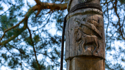 wooden totem pole - pagan slavic or viking warrior symbols with horse and sword carved in wood