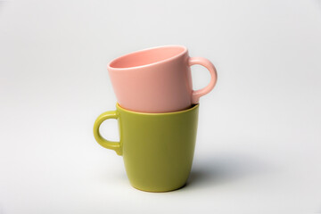 Mockup of a stack of two colorful coffee cups, green and pink, one inside the other, isolated on plain background