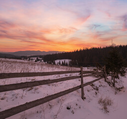 Small alpine village and winter snowy mountains in first sunrise sunlight around, Voronenko, Carpathian, Ukraine.