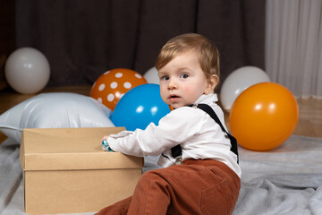 Fototapeta na wymiar A toddler celebrates his first birthday among balloons
