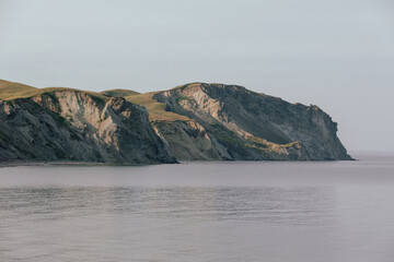 vue sur un rocher gris en bord de mer avec du gazon sur le dessus en été