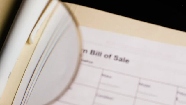 Magnifying glass looking at firearm bill of sale form