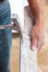 Close up of mason holding piece of stone and a hammer. Stone mason. - obrazy, fototapety, plakaty