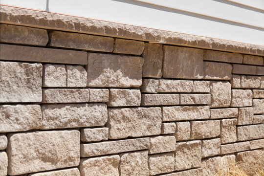 Natural stone veneer instal on the foundation of a home. Stone mason work. Home builder.
